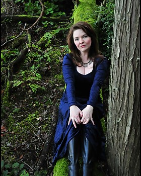 Pale lady in velvet with vampire skin in the twilight woods of Washington